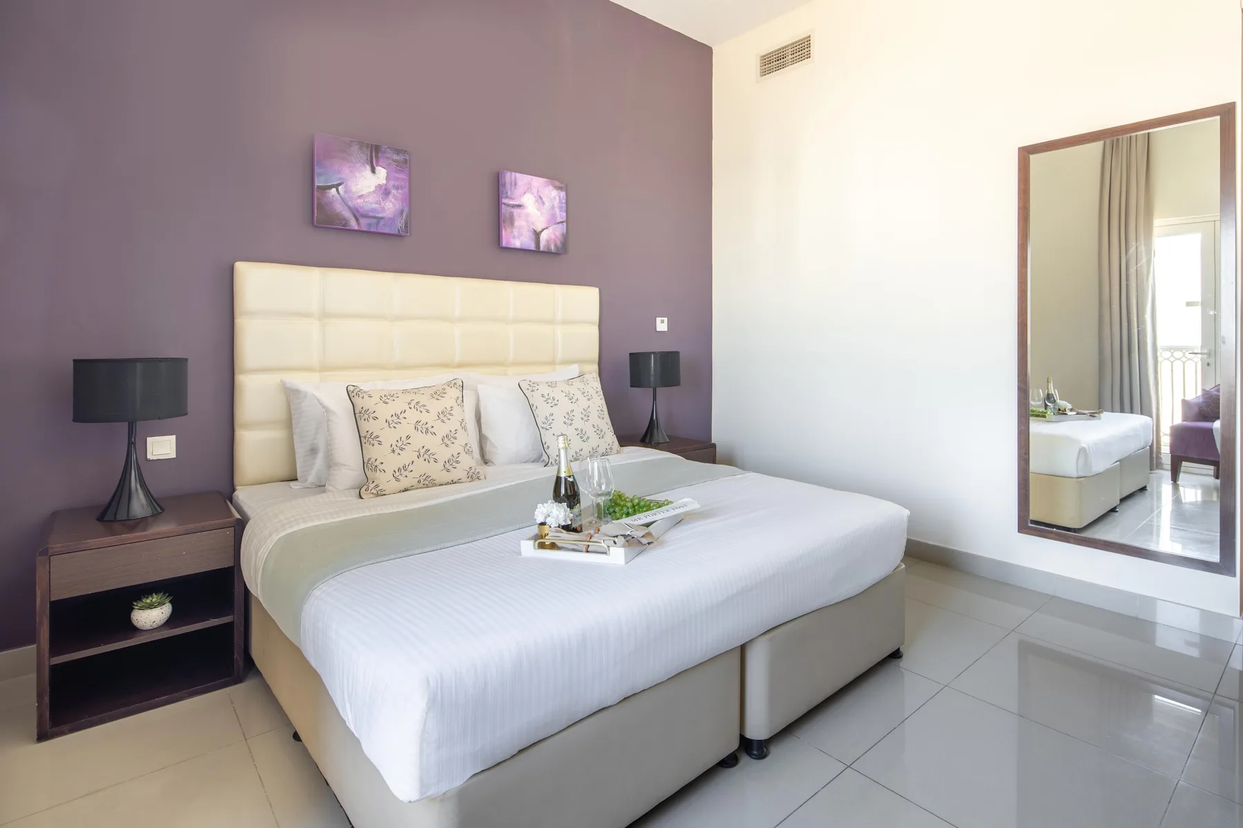A bedroom with a large bed, bedside tables, and artwork on the wall.