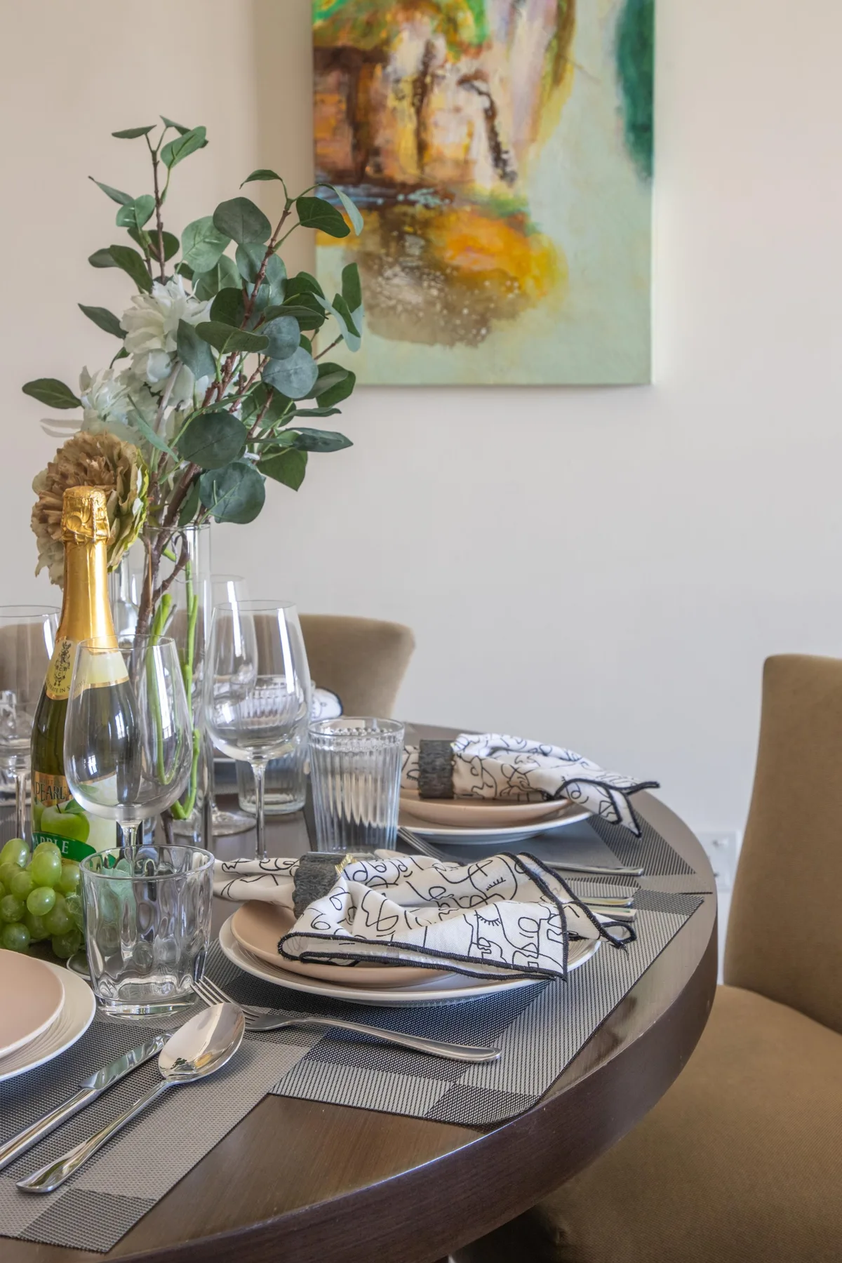 A dining table is set with glassware, folded napkins, and a floral centerpiece.