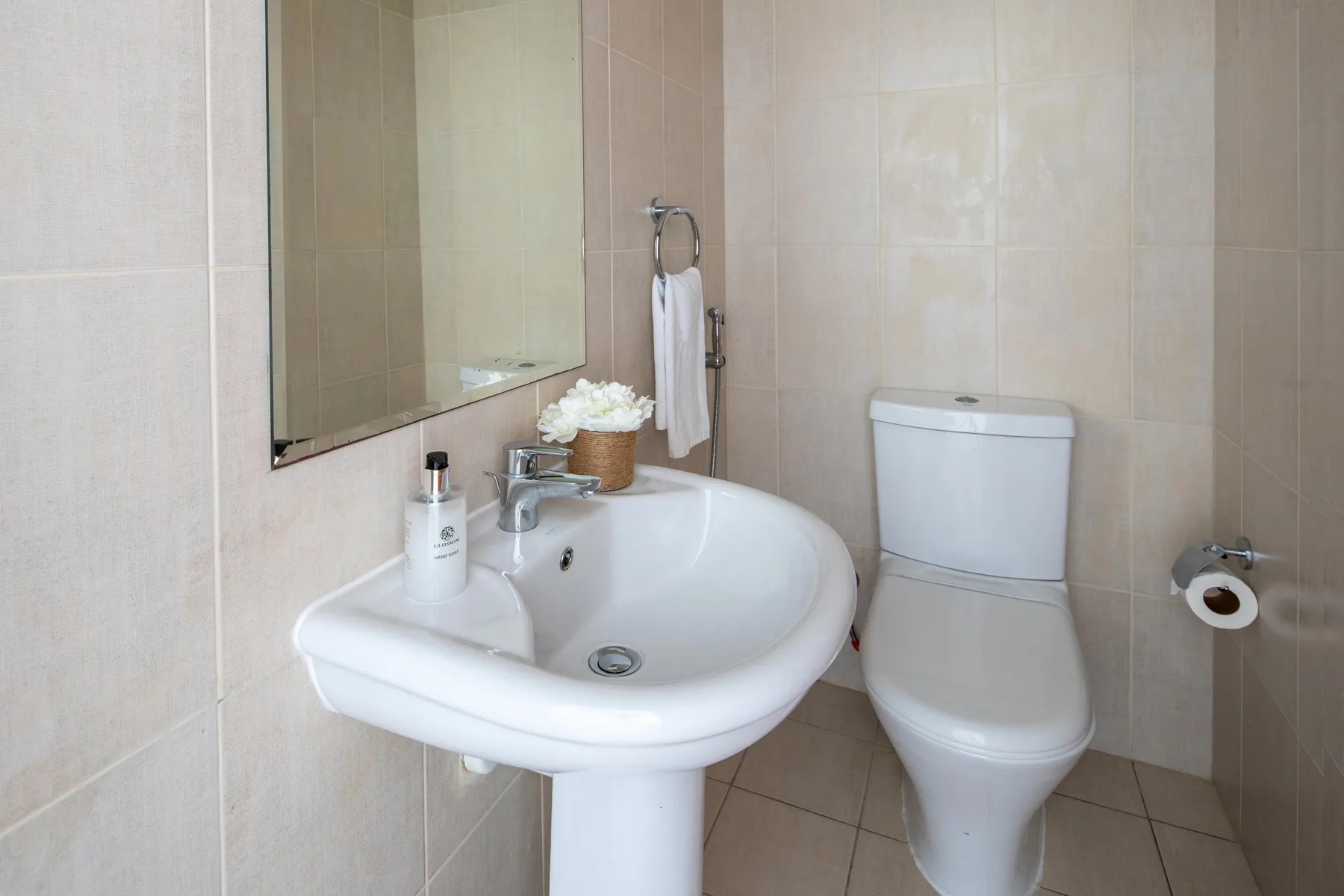 A tiled bathroom with a sink, mirror, and toilet.