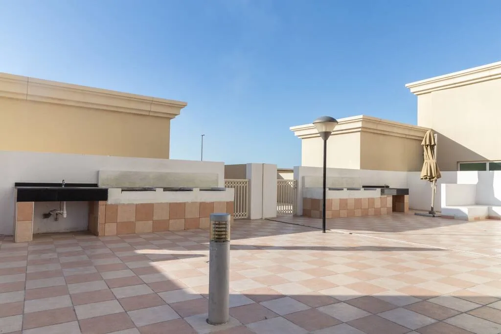 A paved rooftop terrace with low walls, a lamp post, and a folded umbrella.