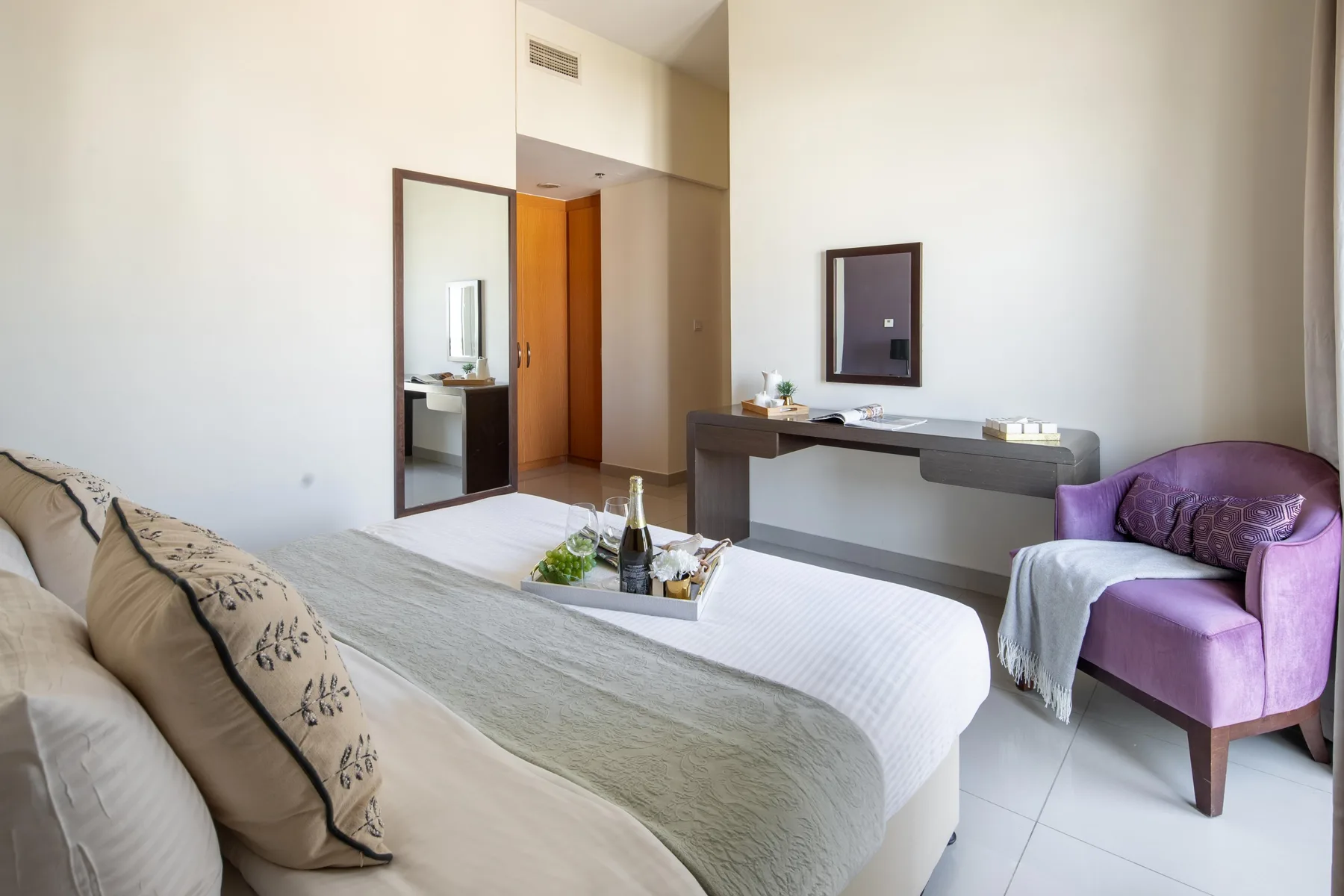 A bedroom with two beds, a desk, and a purple armchair.
