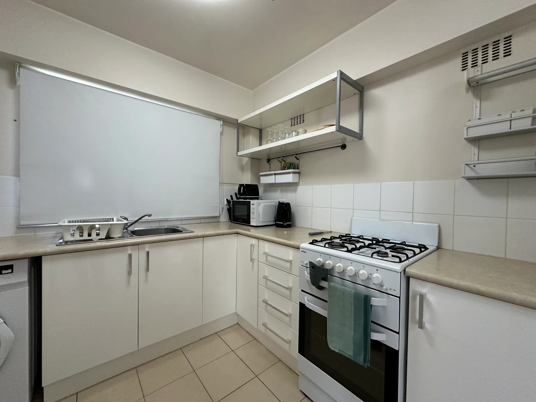 Una cocina compacta con una estufa de gas, horno y fregadero.