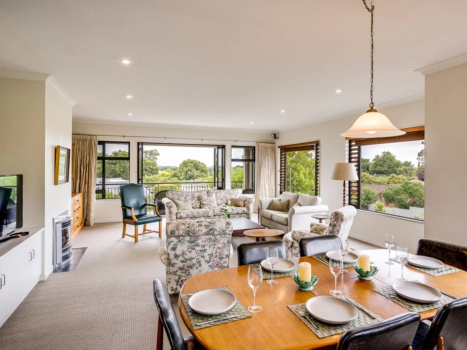 A dining area with set table and a living room with sofas and chairs at Busby Hill Villa in Havelock North