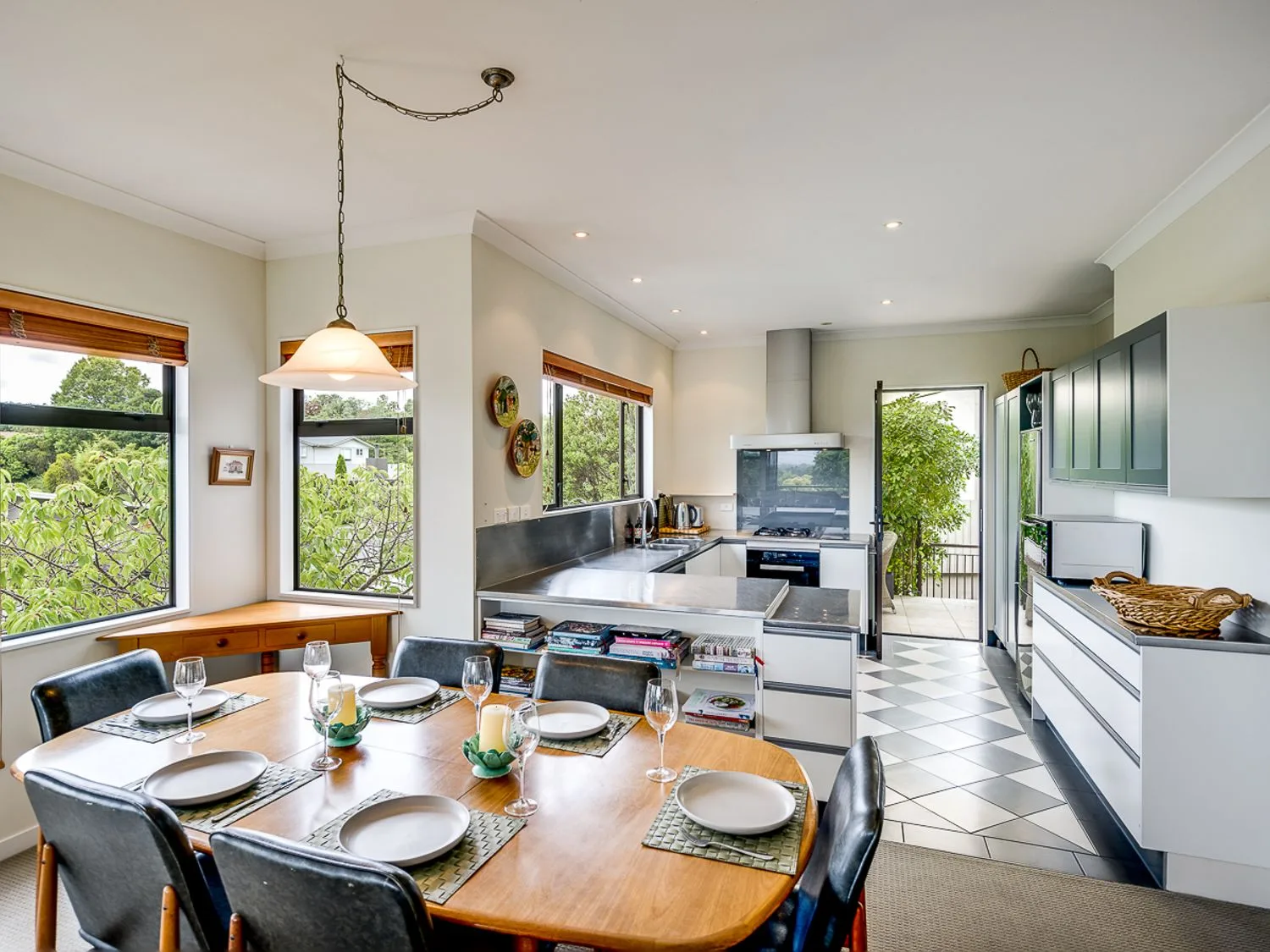A kitchen and dining area with a wooden table set with plates and glasses at Busby Hill Villa - Havelock North Holiday Home in Havelock North