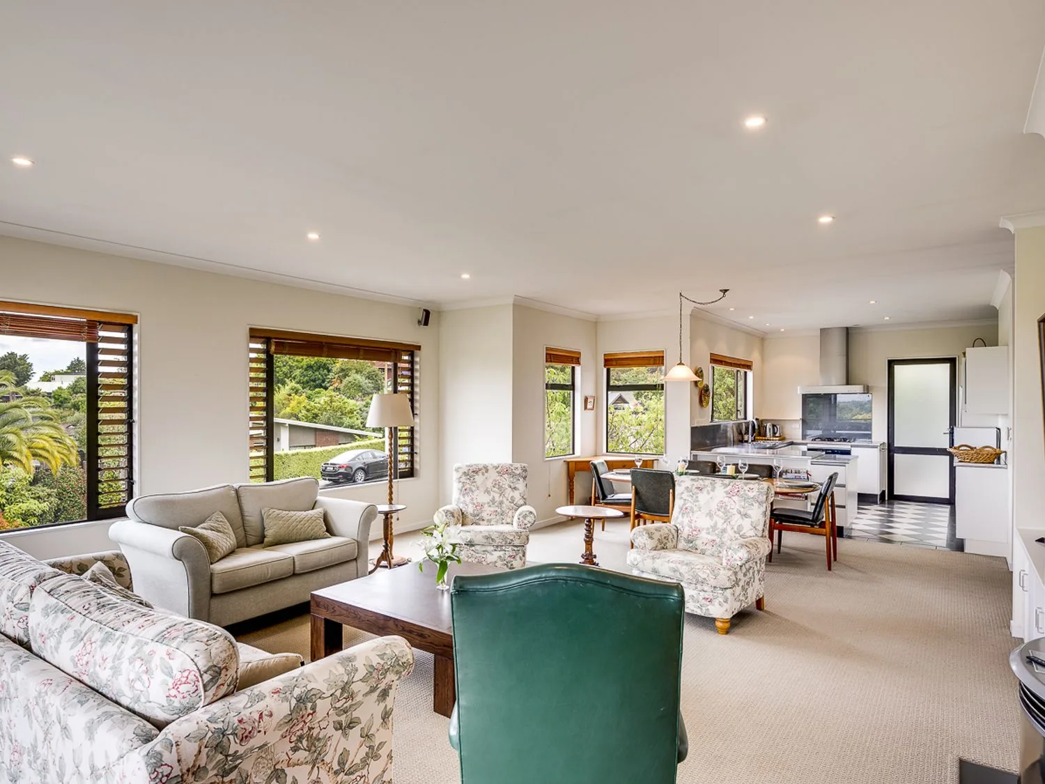 An open living room and kitchen area with sofas armchairs a dining table and kitchen appliances at Busby Hill Villa - Havelock North Holiday Home in Havelock North