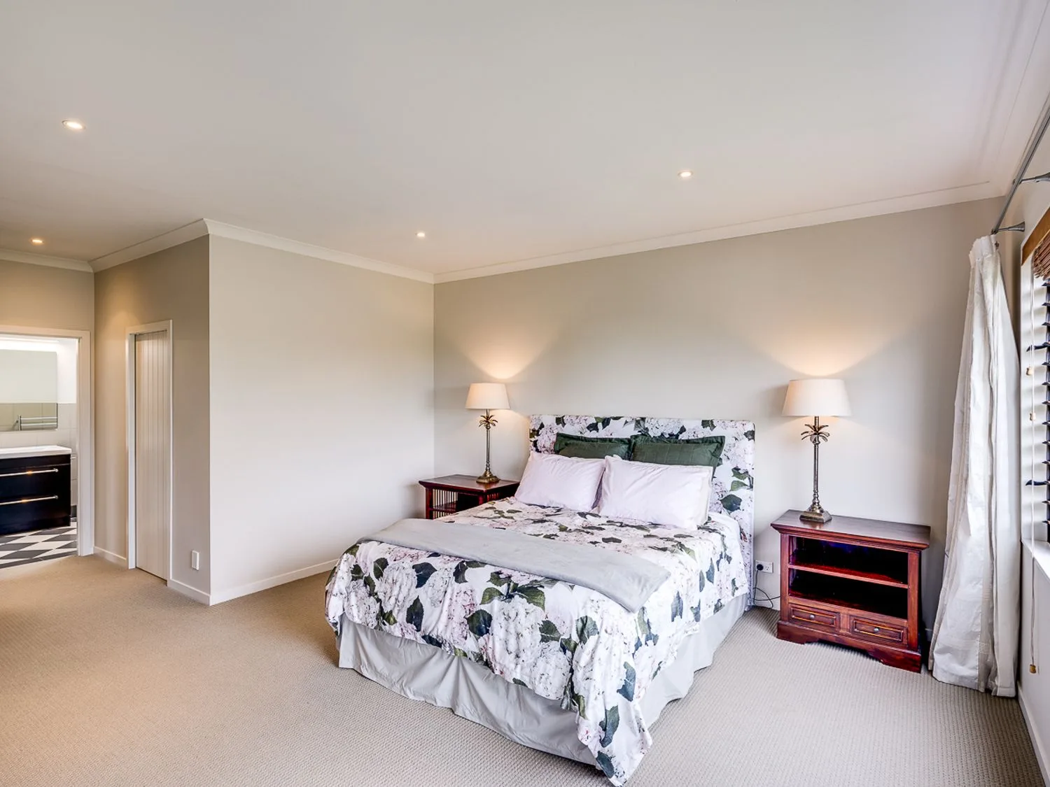 A bedroom with a floral-patterned bedspread and bedside tables topped with lamps.