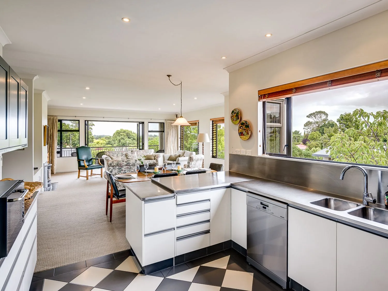 A kitchen and dining area with a sink dishwasher and table set for four at Busby Hill Villa in Havelock North