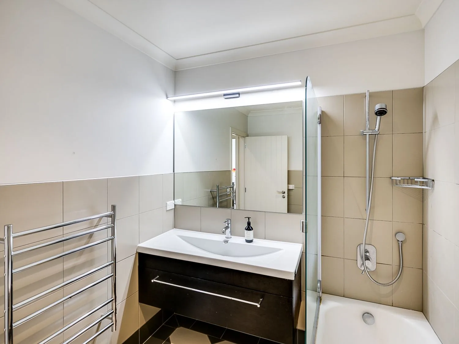 A bathroom with a sink and mirror a shower over a bathtub and a towel rack at Busby Hill Villa - Havelock North Holiday Home in Havelock North
