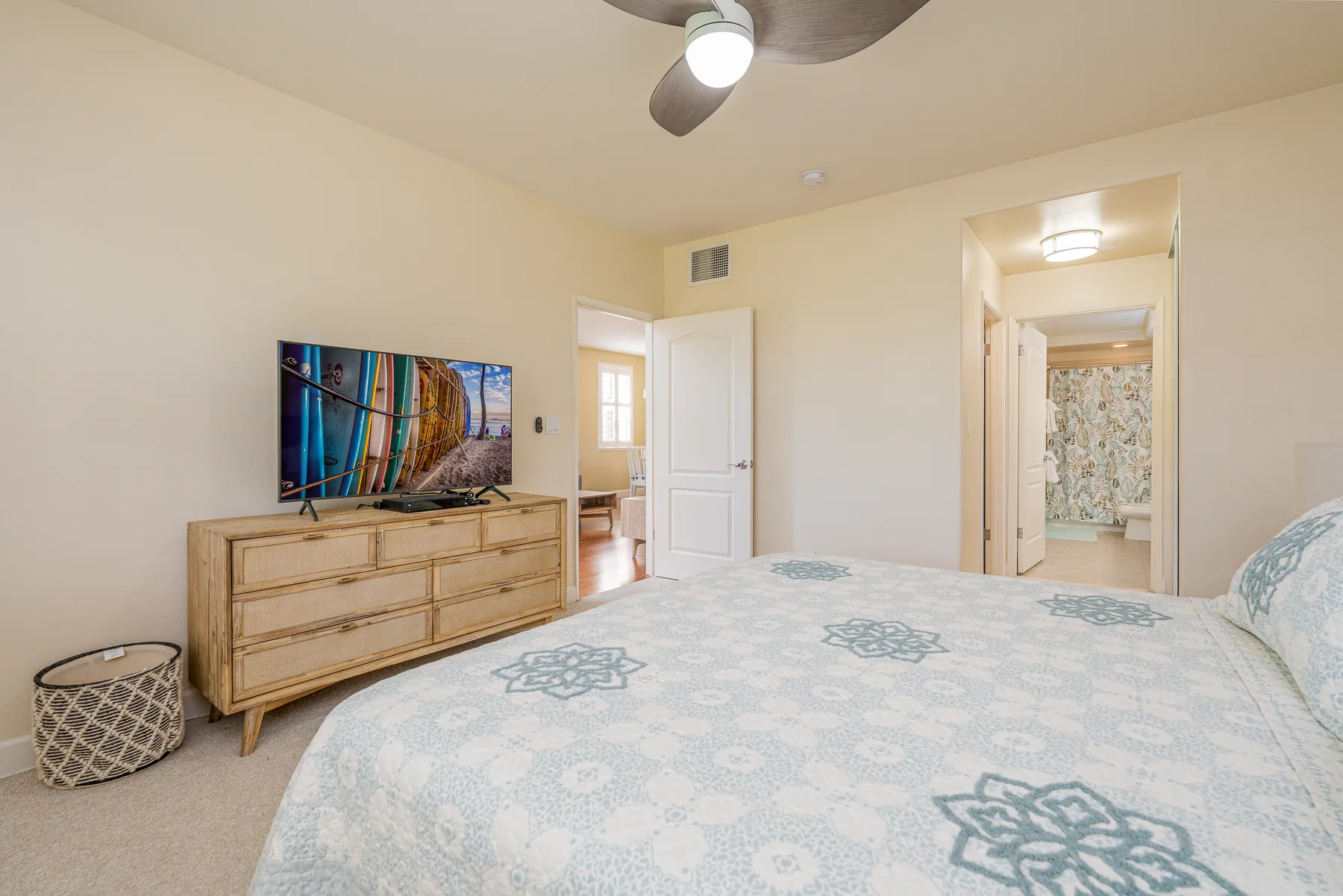 A bedroom with a patterned bedspread and a dresser topped by a television.