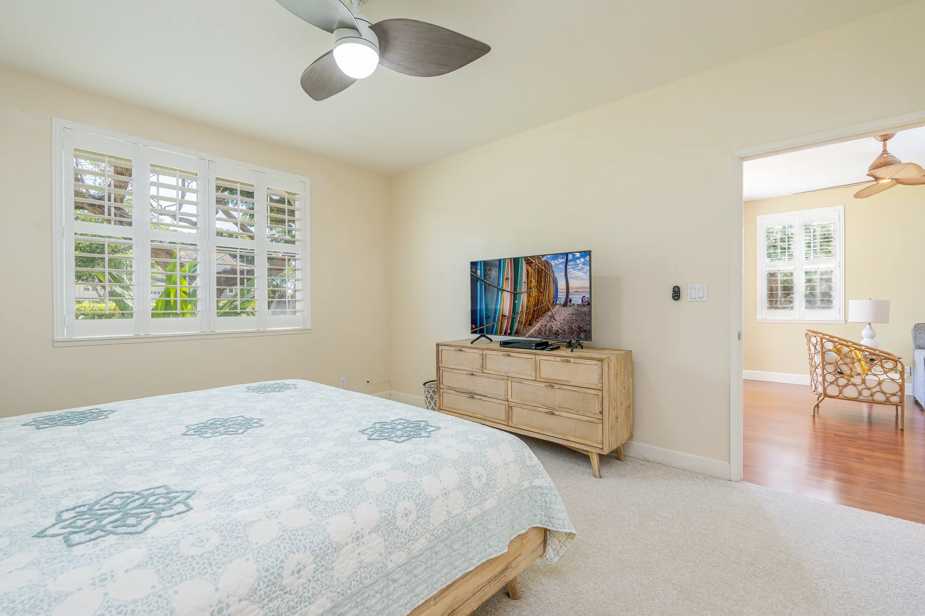 A bedroom with a bed, a television on a dresser, and windows.