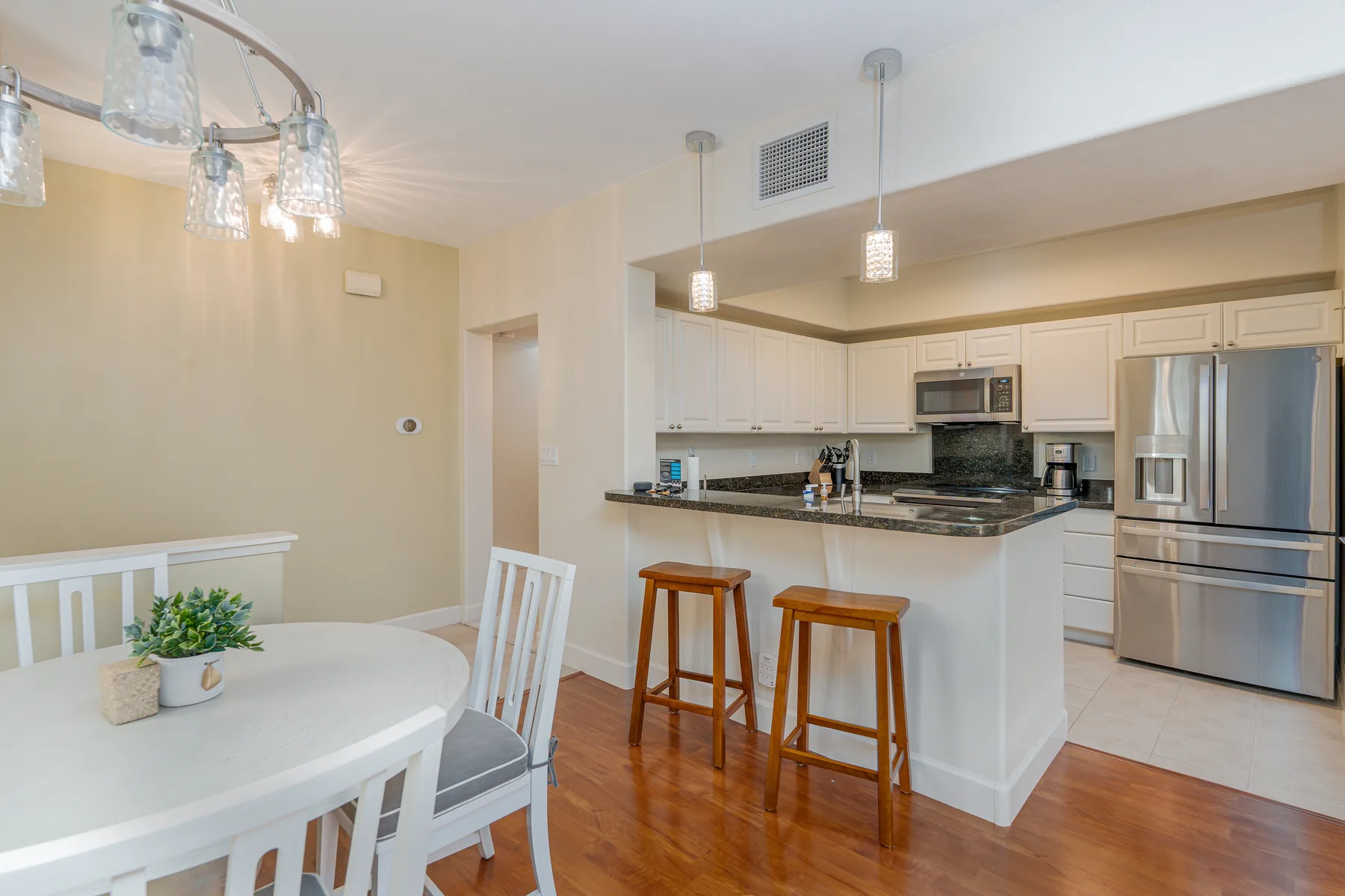 A dining area opens onto a kitchen with a dark countertop and bar stools.