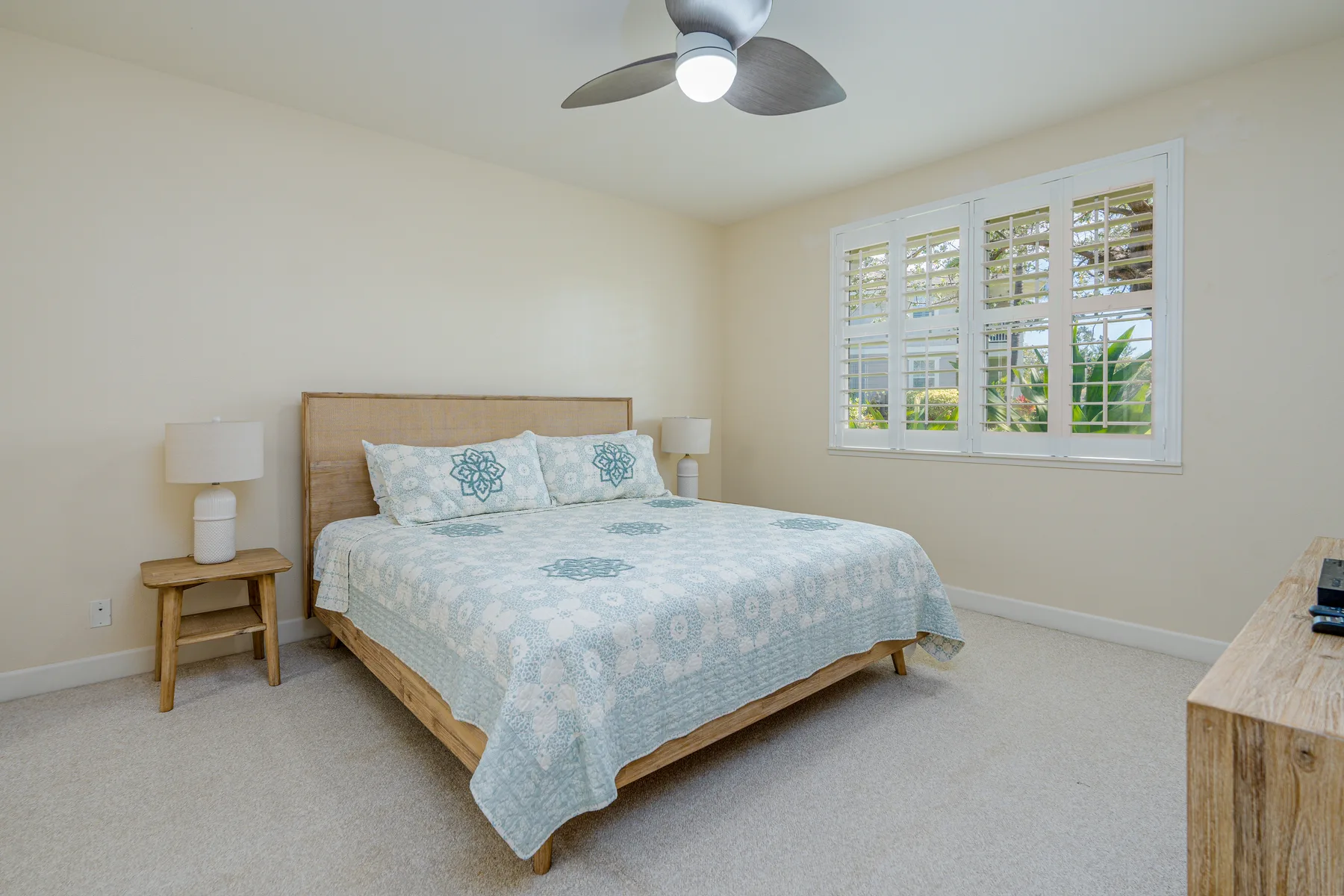A bedroom with a bed beside a window with white shutters.