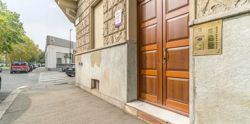 A building entrance with wooden double doors beside a sidewalk.