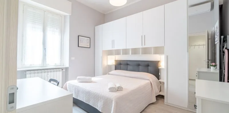 A bright bedroom with a neatly made bed and built-in wardrobes.