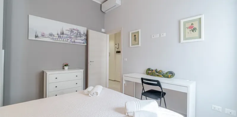 A bedroom with a bed, a dresser, and a desk against the wall.
