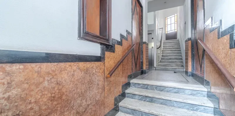 A stairwell with stone steps and wooden handrails.