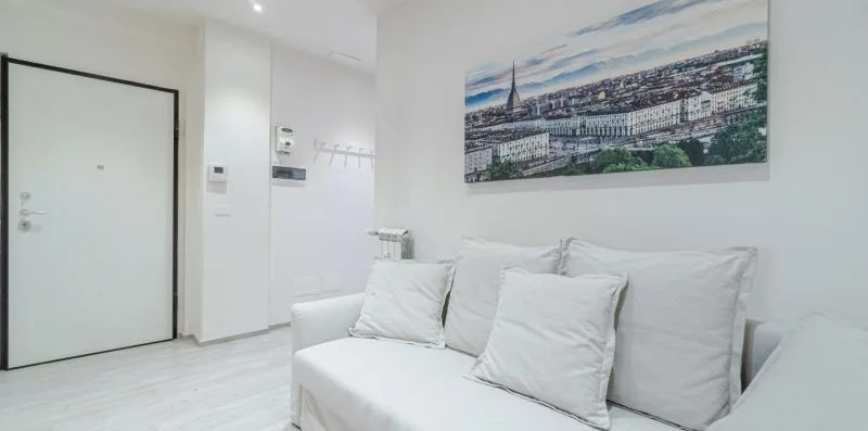 A bright white room with a sofa and a panoramic cityscape picture on the wall.