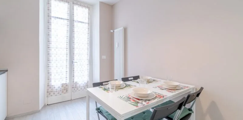 A dining area with a table set beside tall windows.