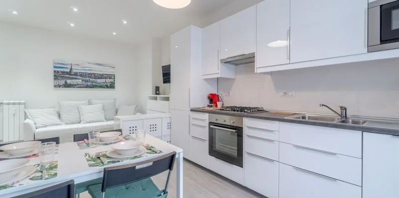 A bright kitchen with white cabinetry and a dining table.