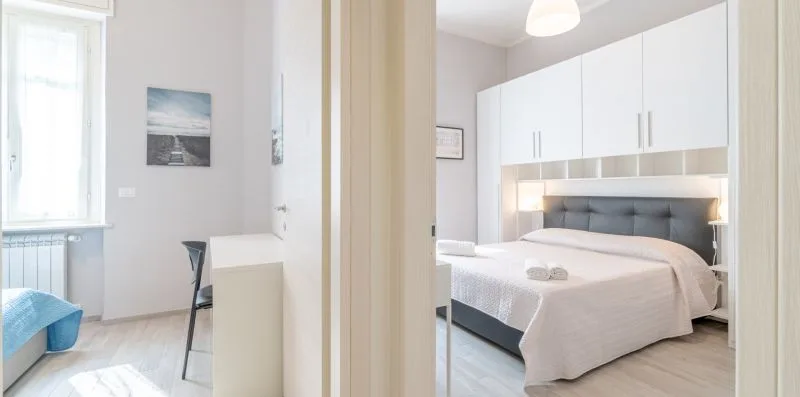 A bedroom with a neatly made bed and white cabinetry above the headboard.