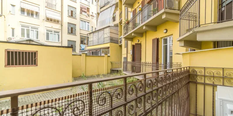 An apartment courtyard with yellow walls, balconies, and decorative metal railings.