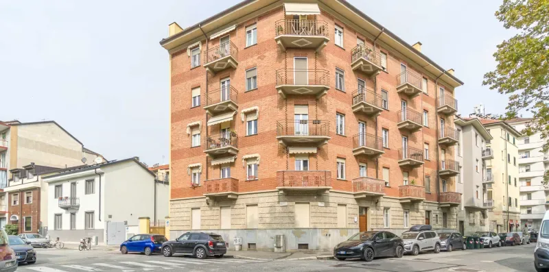 A red-brick apartment building with balconies stands along a city street.