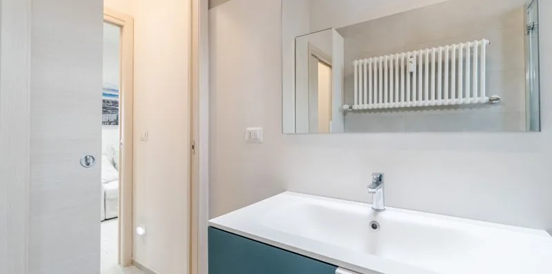 A bathroom vanity with a wide mirror and a wall-mounted towel radiator.