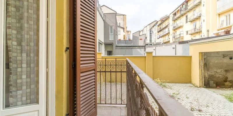 A small balcony overlooks a paved courtyard and nearby apartment buildings.