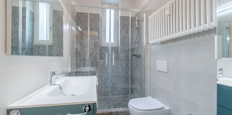 A bright bathroom with a glass shower, sink, and toilet.