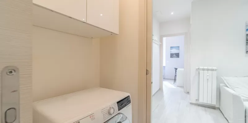 A bright interior hallway connects a laundry area with an adjoining room.