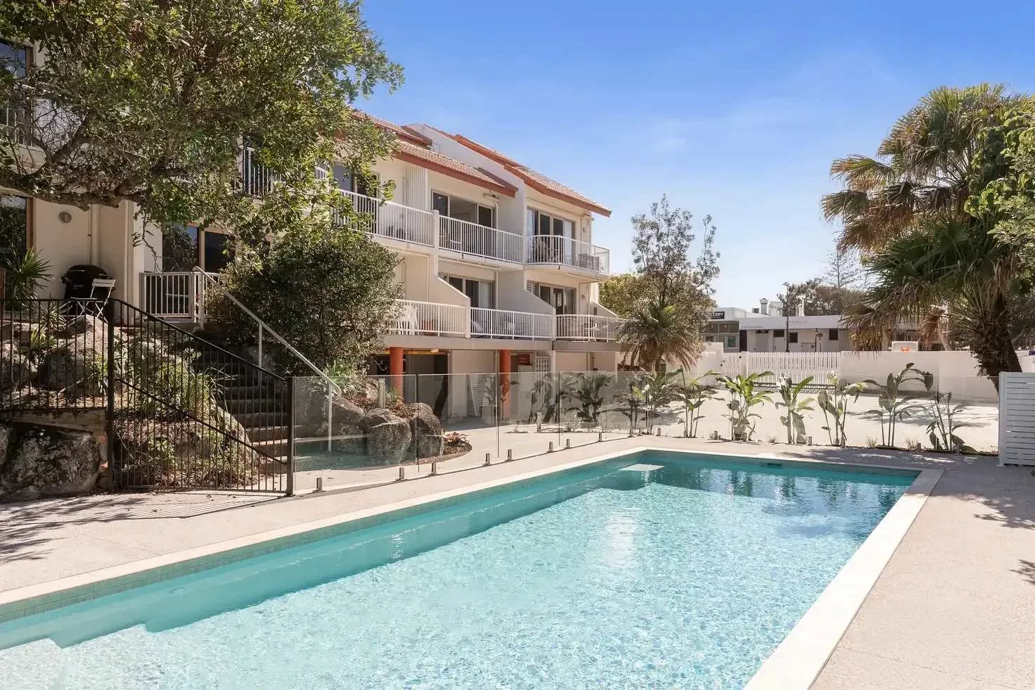 Piscina al aire libre junto a un edificio de varios pisos con balcones.