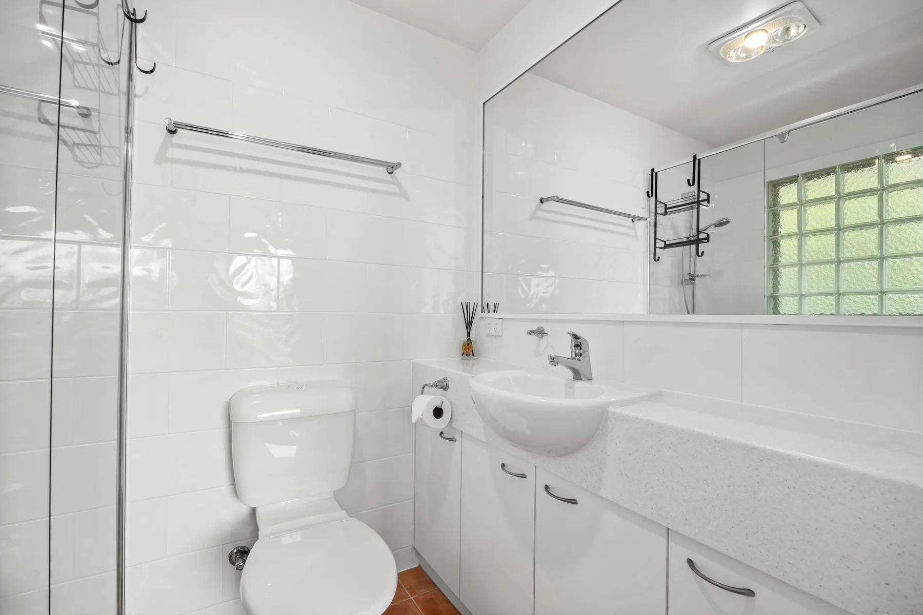 Un baño luminoso con azulejos, lavabo, inodoro y un espejo grande.