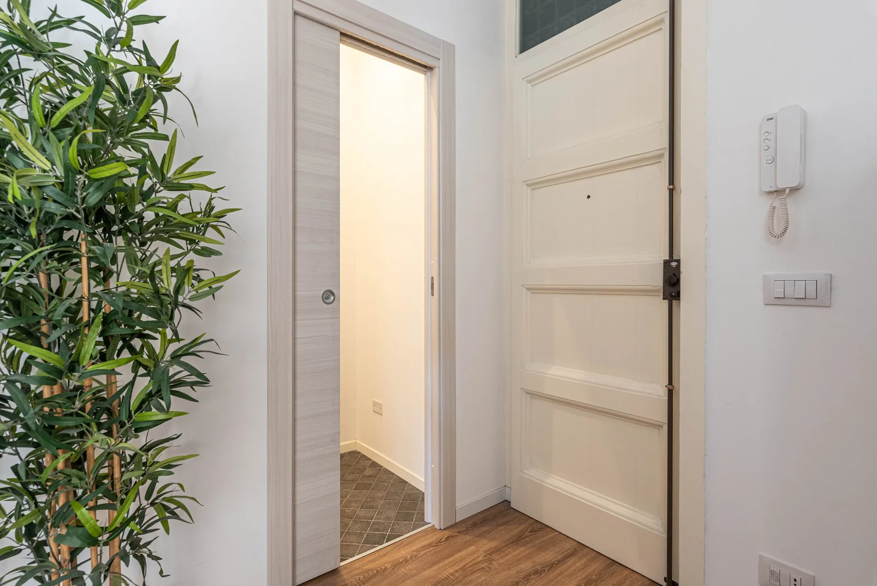 Una entrada con una puerta abierta, la puerta principal y una planta alta.