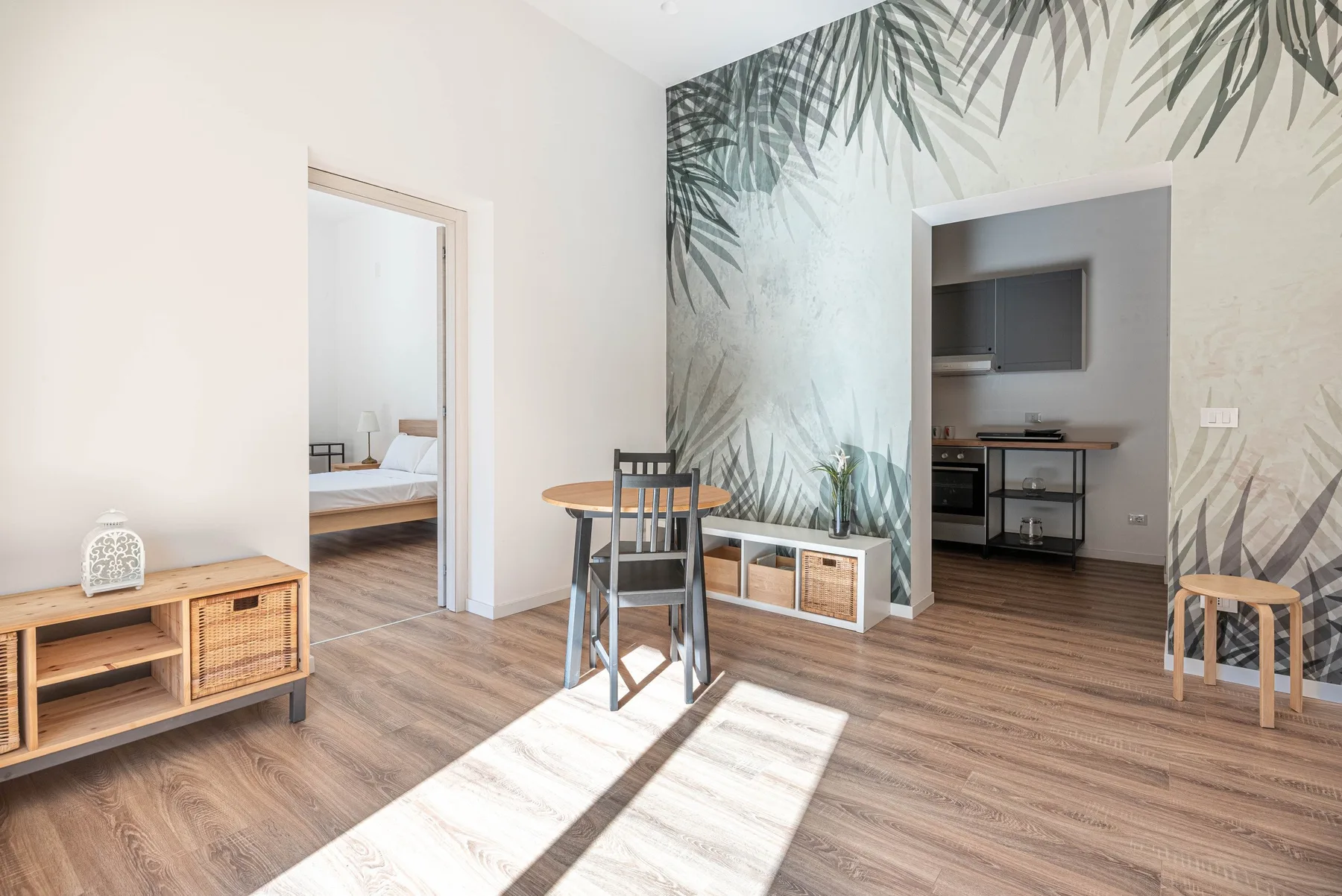 Un comedor con una mesa y sillas junto a una pared con motivos de hojas.