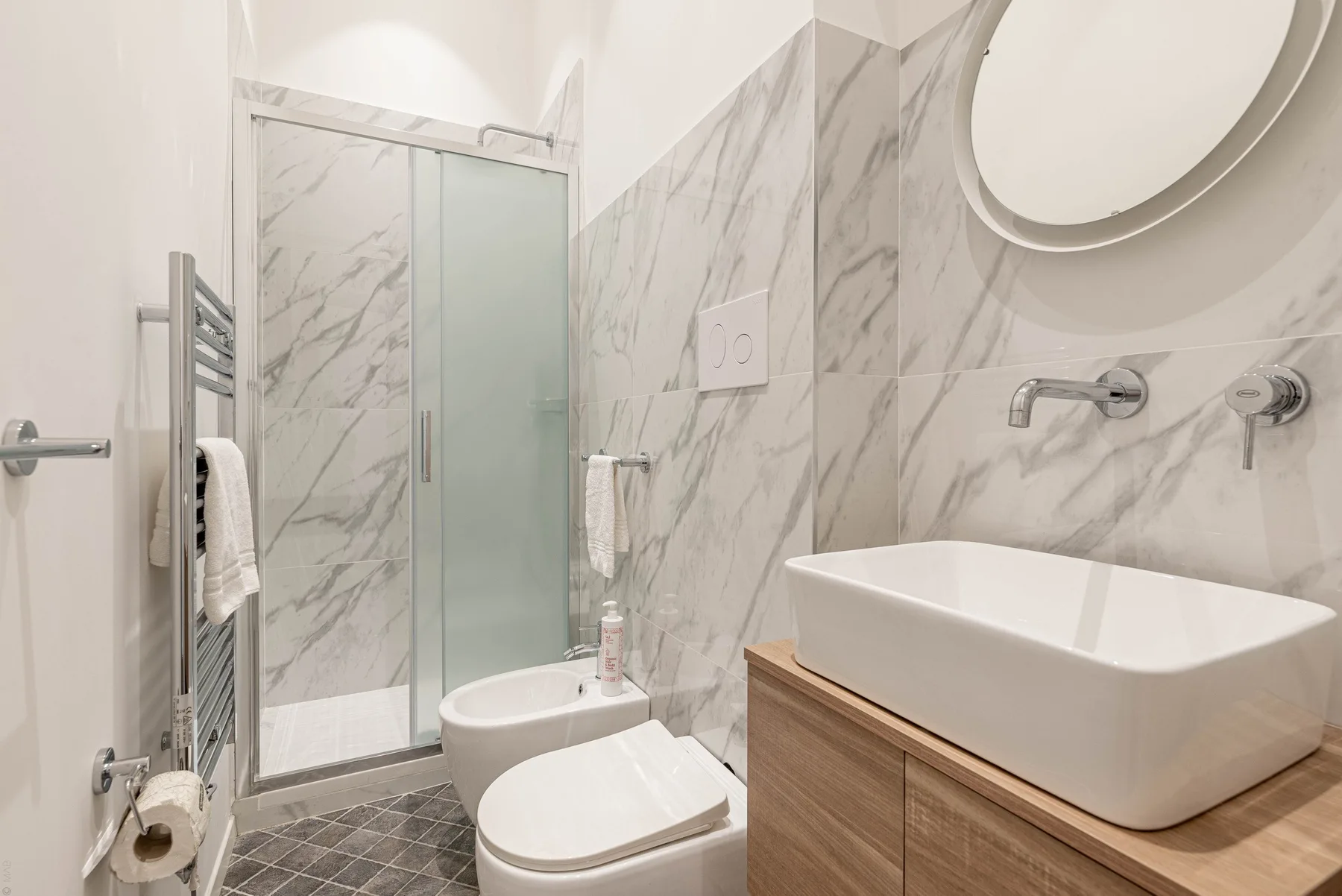 Un baño luminoso con ducha de vidrio, inodoro y lavabo sobre encimera.