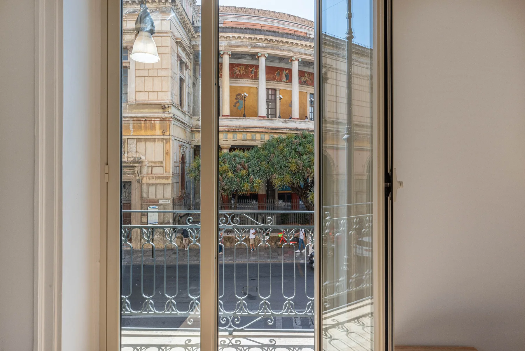 Vista a través de ventanas altas hacia una calle y un edificio ornamentado.