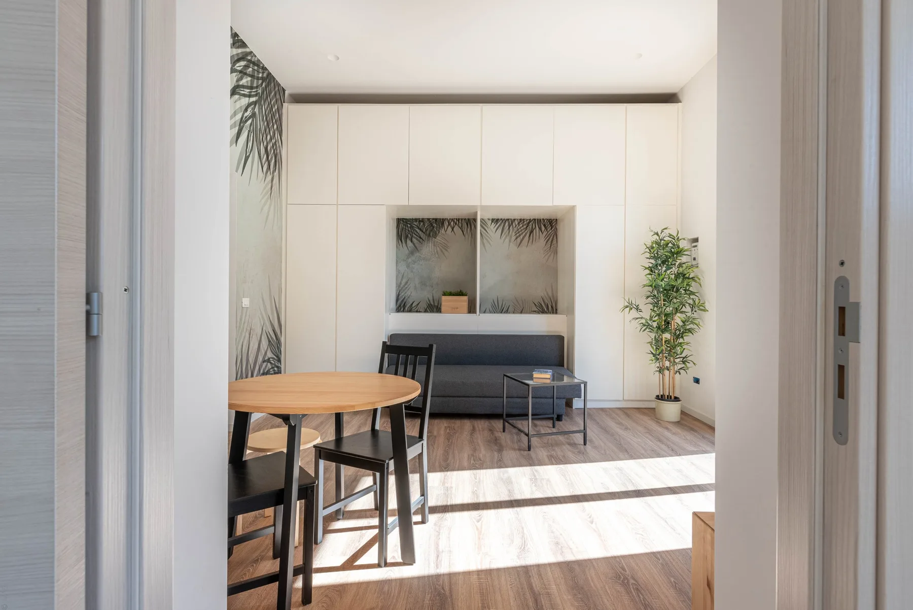 Una sala de estar luminosa con una mesa, asientos y una planta en maceta.