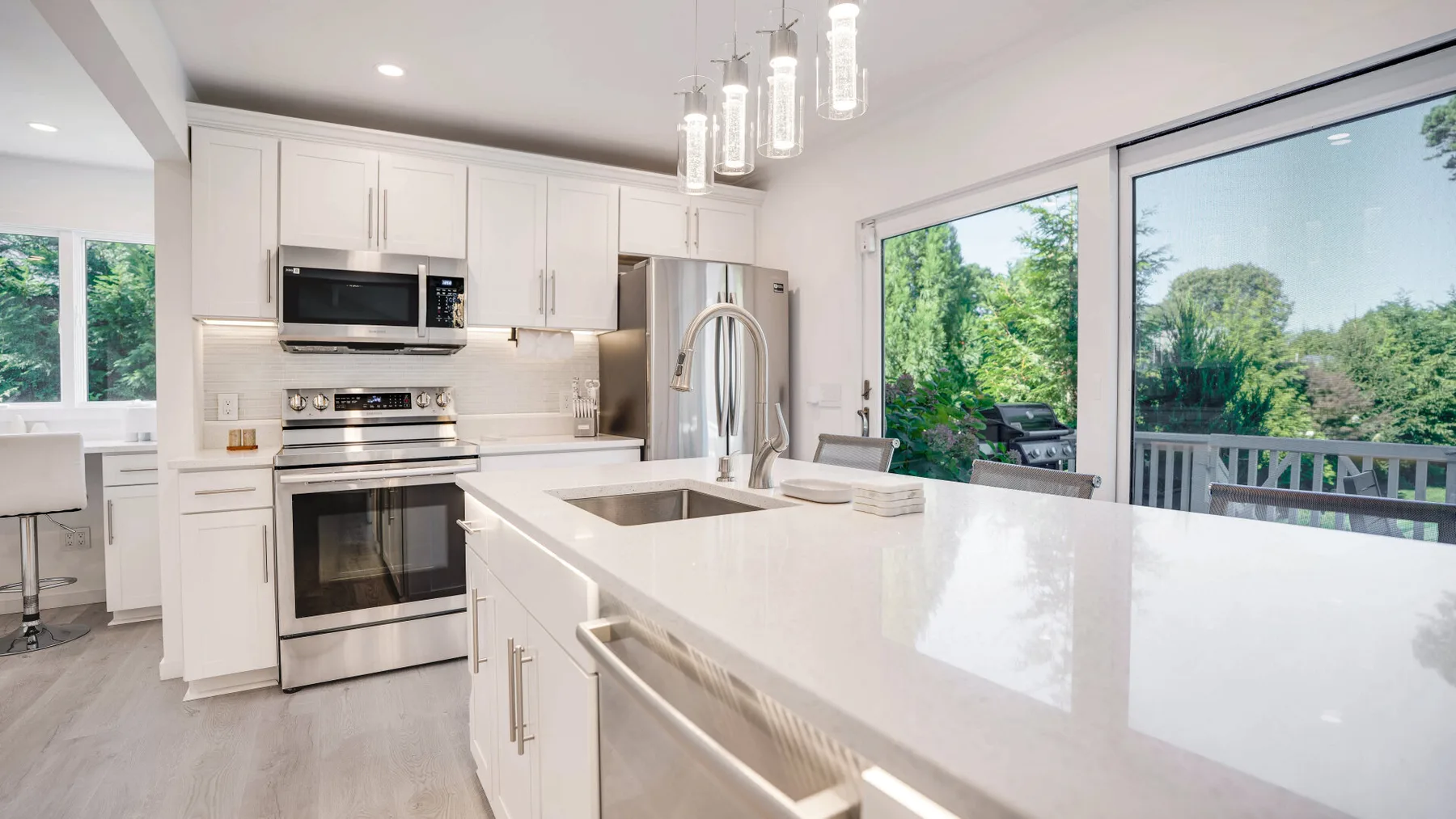 Una cocina luminosa con gabinetes blancos, electrodomésticos de acero inoxidable y una isla amplia.