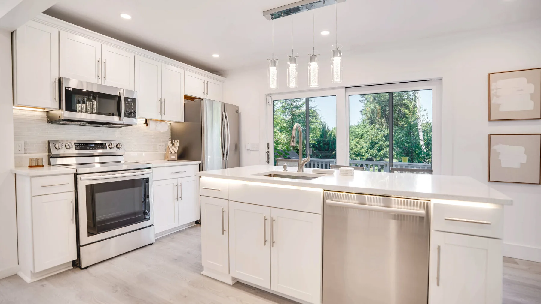 Una cocina luminosa con gabinetes blancos, una isla central y ventanales.