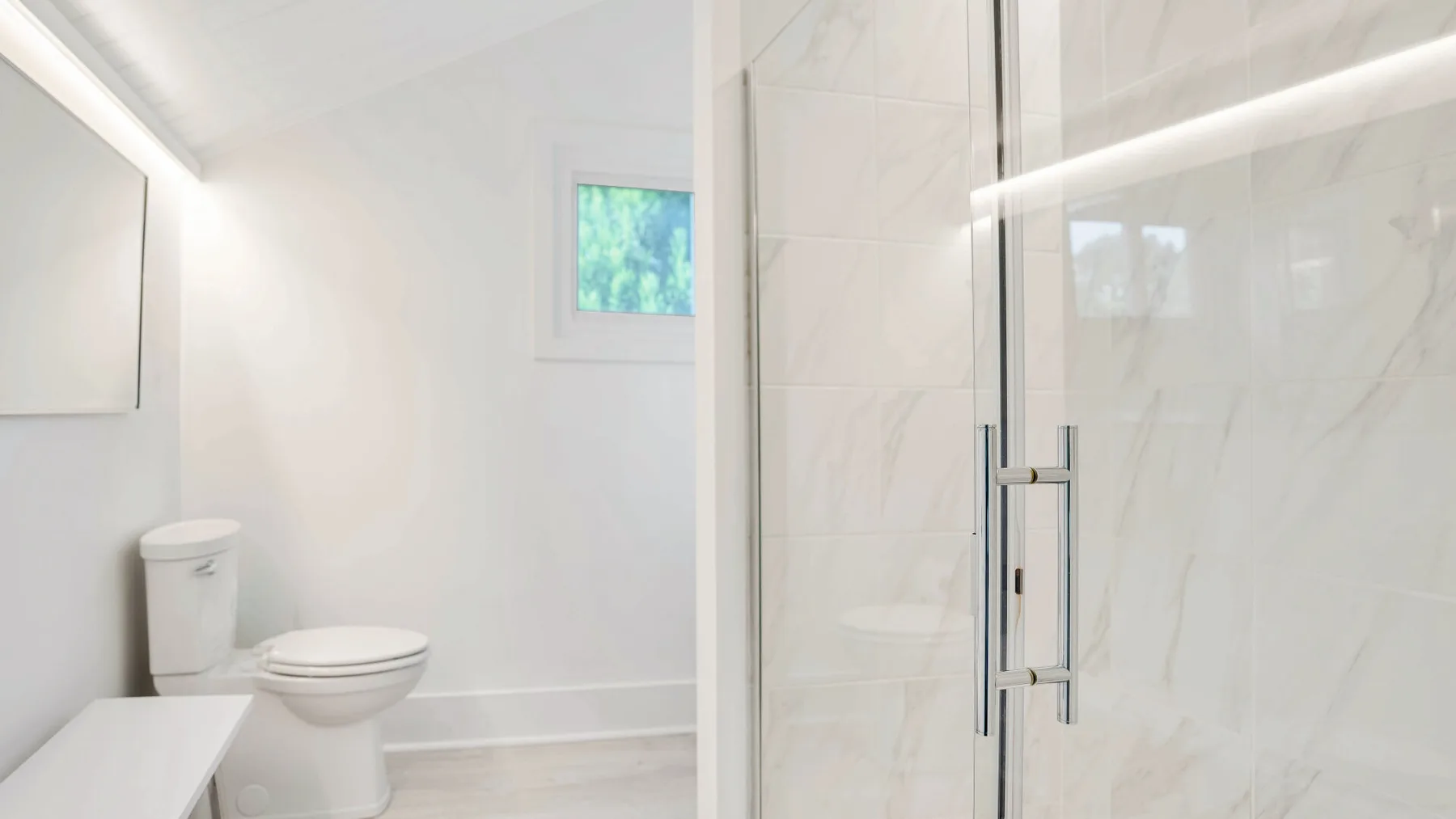 Un baño luminoso con inodoro, lavabo y ducha de vidrio.
