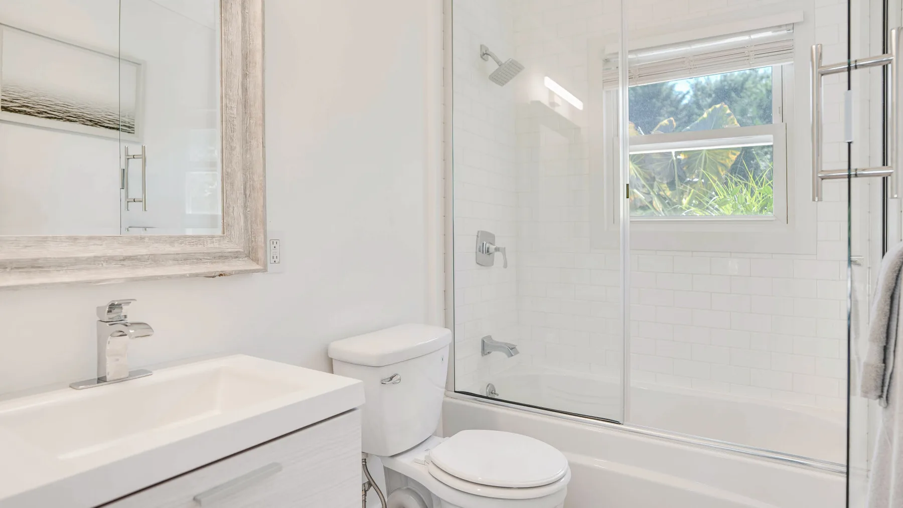 Un baño luminoso con lavabo, inodoro y bañera bajo una ventana.