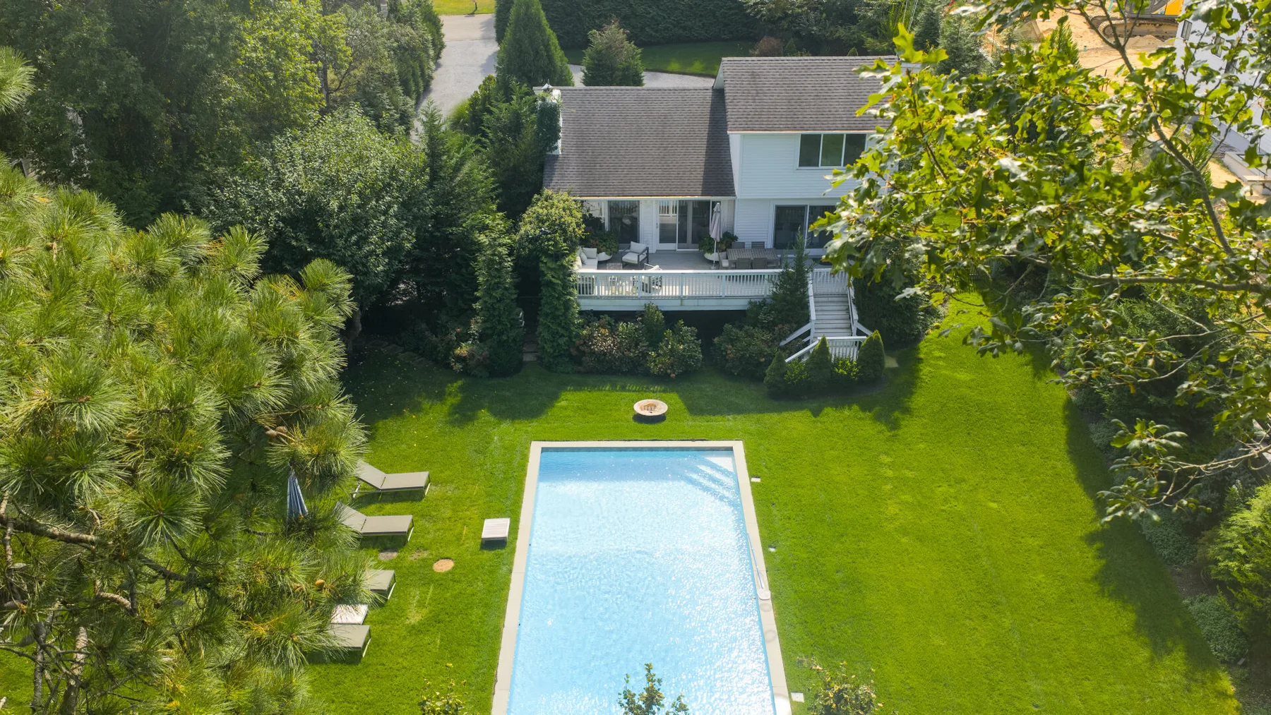 Una casa da a una piscina rodeada por un amplio césped verde.