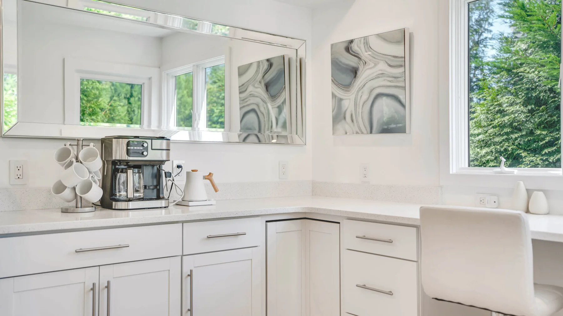 Una cocina luminosa con una cafetera sobre la encimera y una ventana grande.
