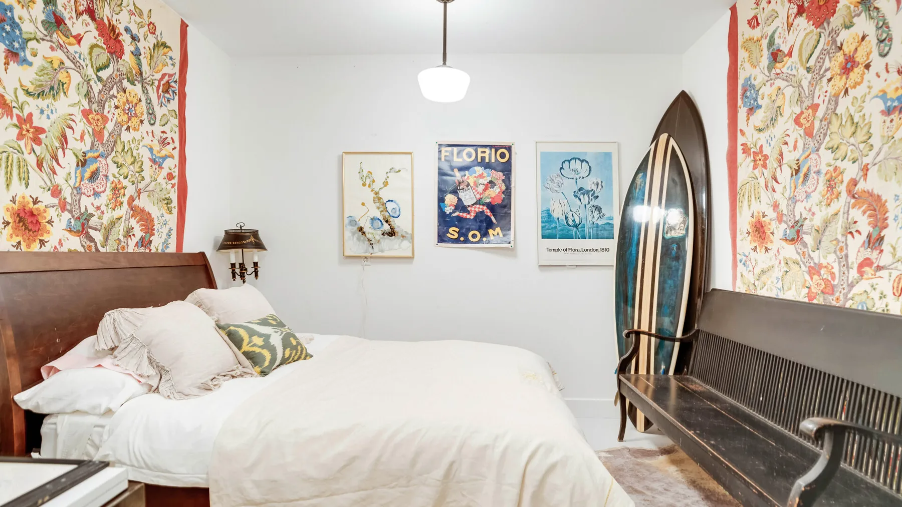 Un dormitorio con una cama, cortinas florales y cuadros en la pared.