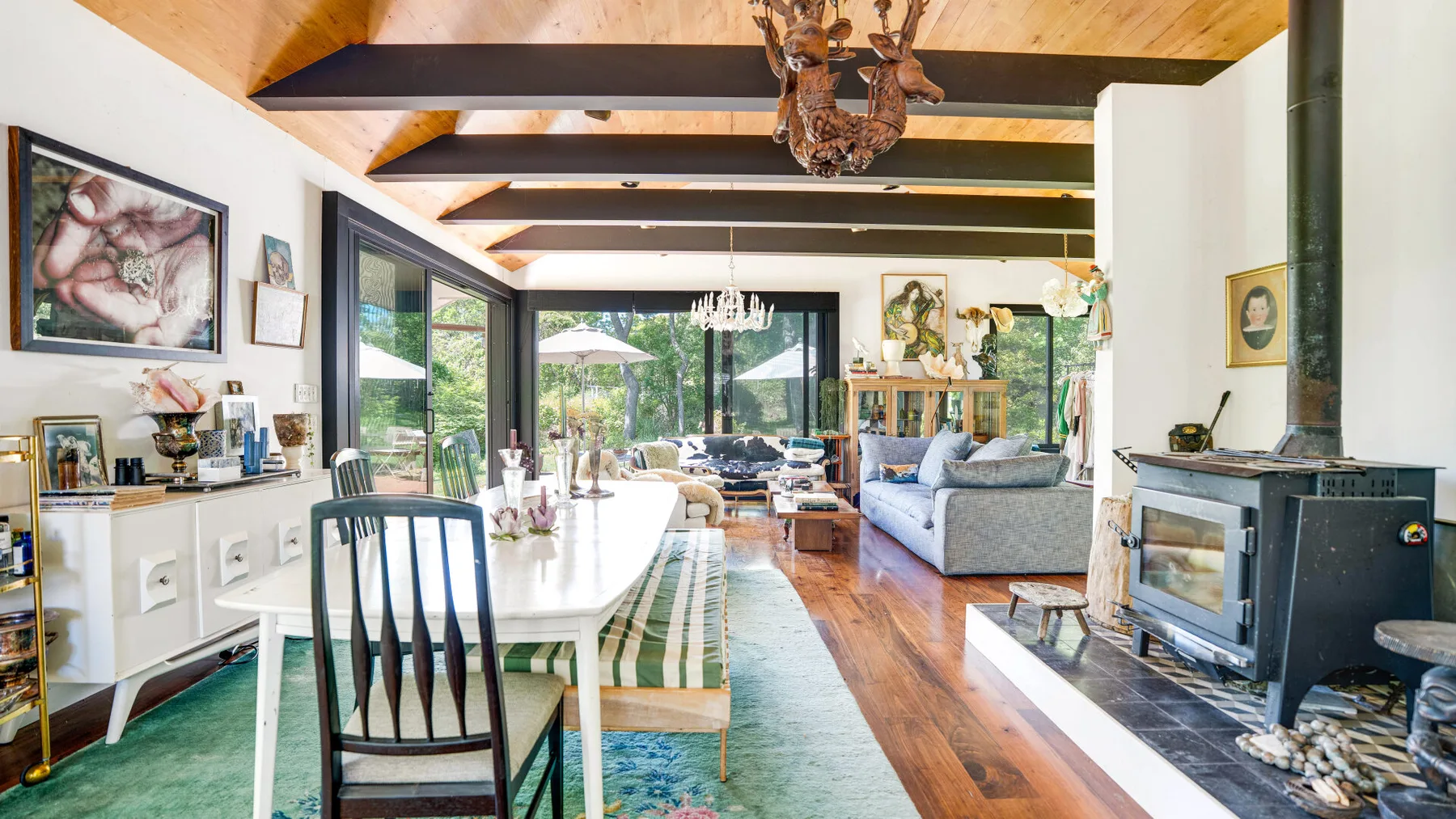 Una luminosa sala de estar y comedor tiene vigas de madera a la vista y grandes ventanas.