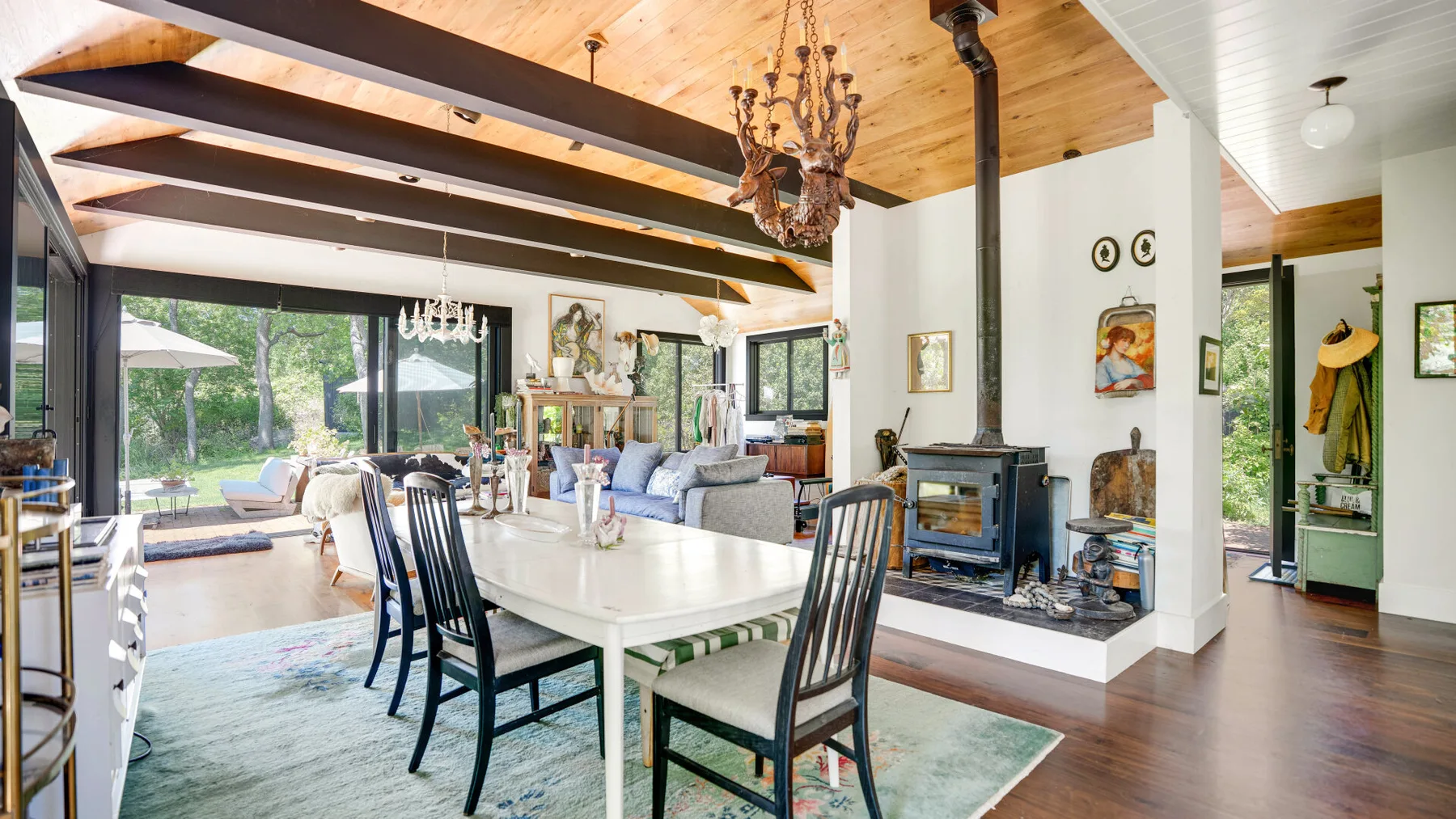 Un espacio abierto de comedor y sala con una mesa larga y asientos junto a grandes ventanas.