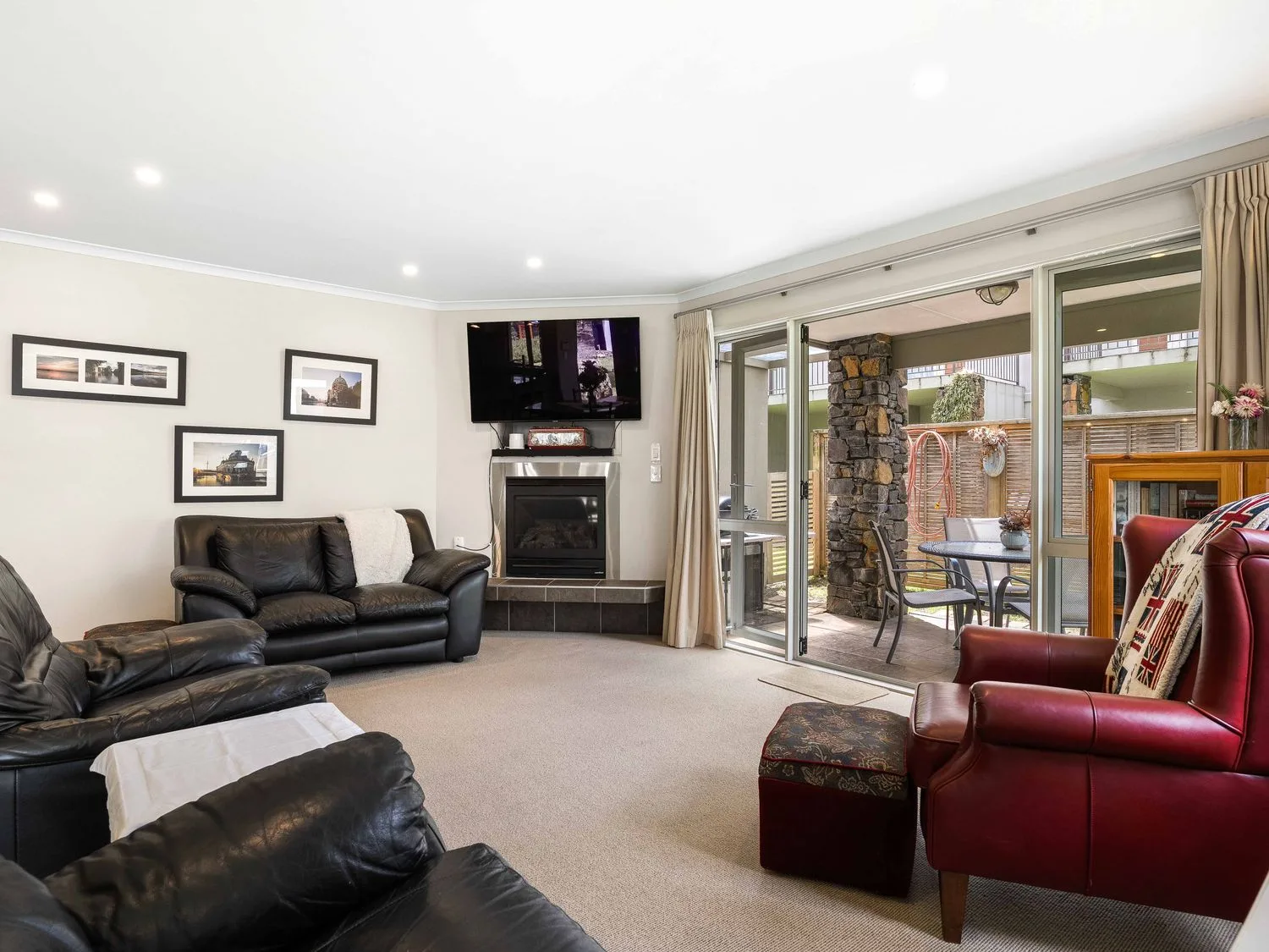 Una sala de estar con sofá, televisor y chimenea en Sue's Holiday Home - Pauanui