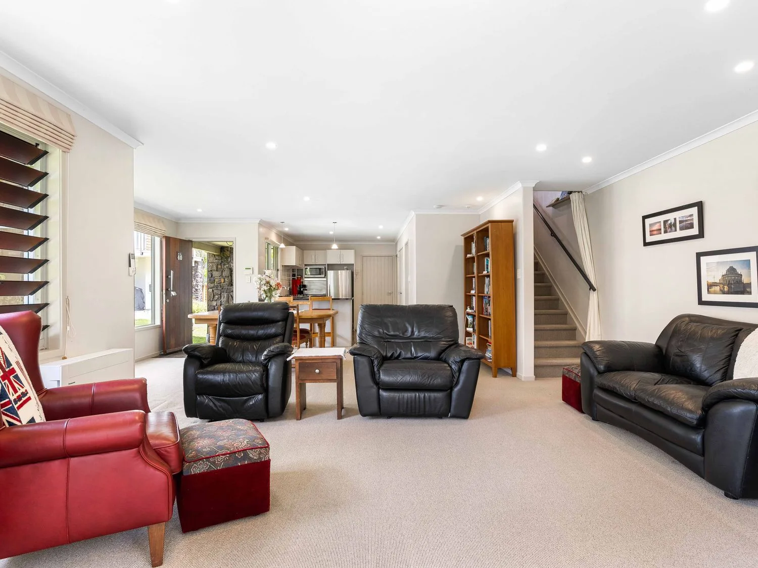 Una sala de estar con sillones de cuero y una mesa de madera en Sue's Holiday Home - Pauanui
