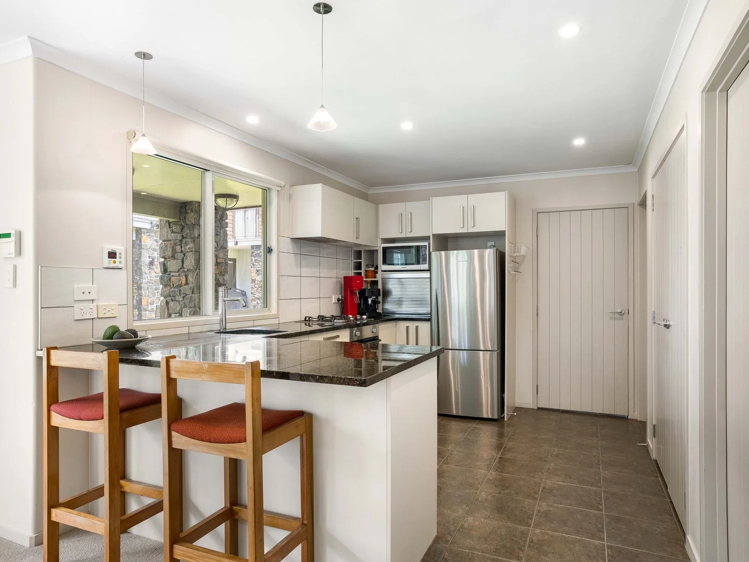 Una cocina con refrigerador y taburetes de bar en Sue's Holiday Home - Pauanui Holiday Home