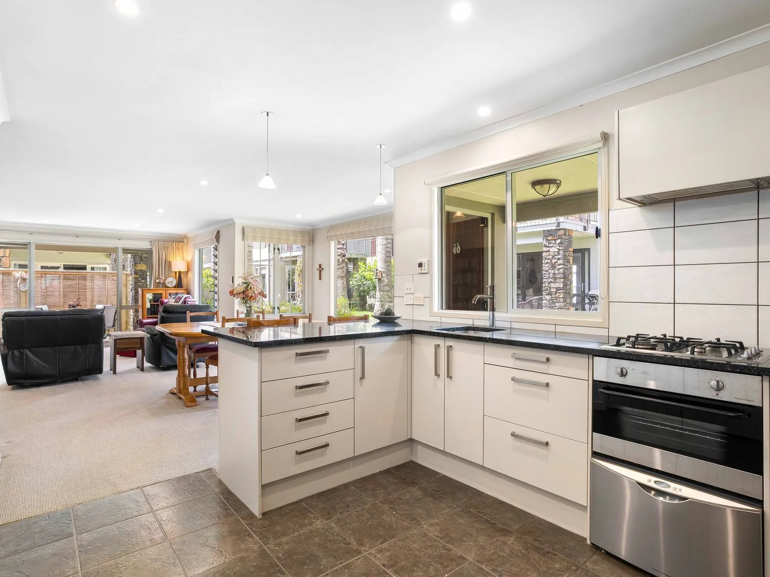 Una cocina con electrodomésticos y zona de comedor en Sue's Holiday Home - Pauanui